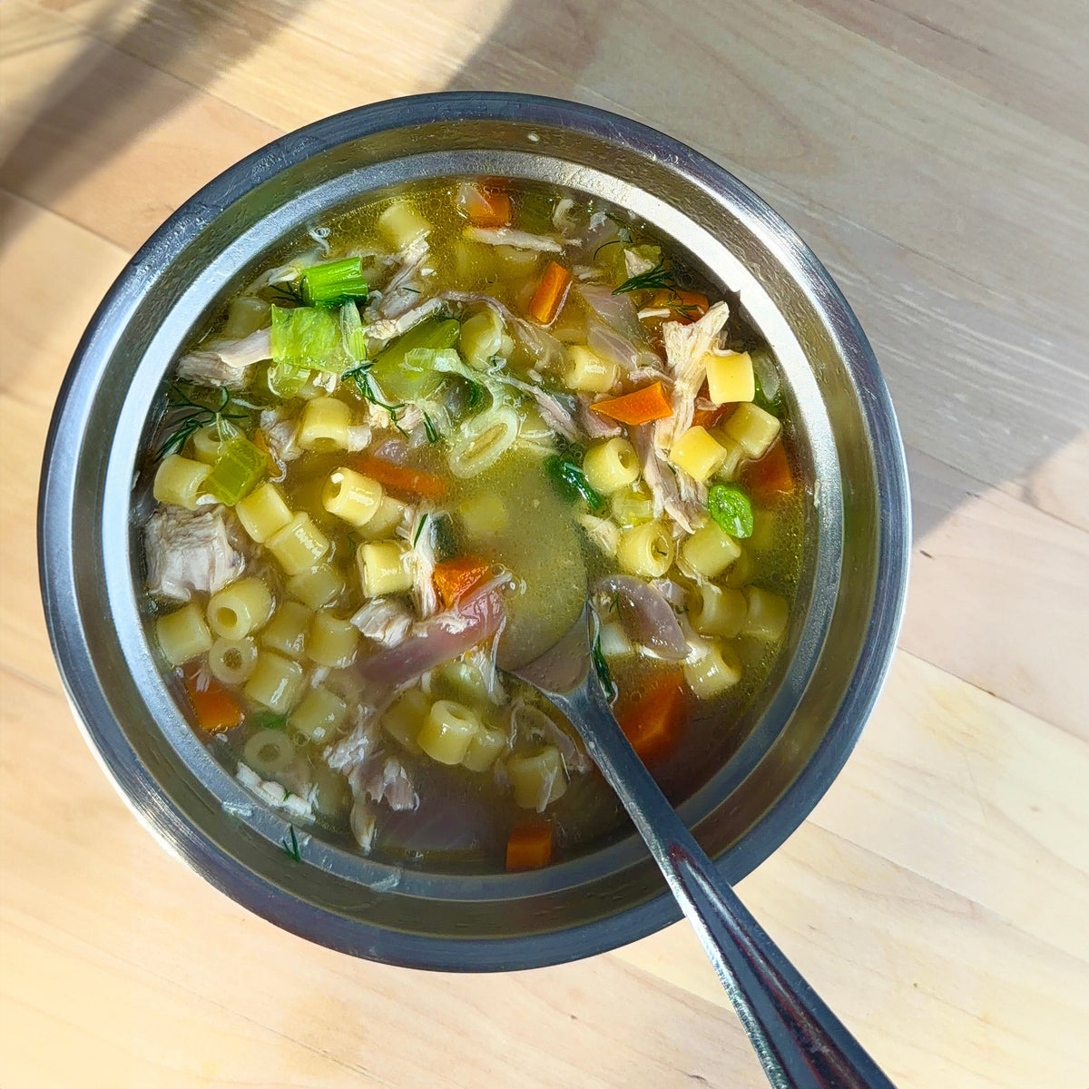 a bowl of chicken noodle soup with a spoon