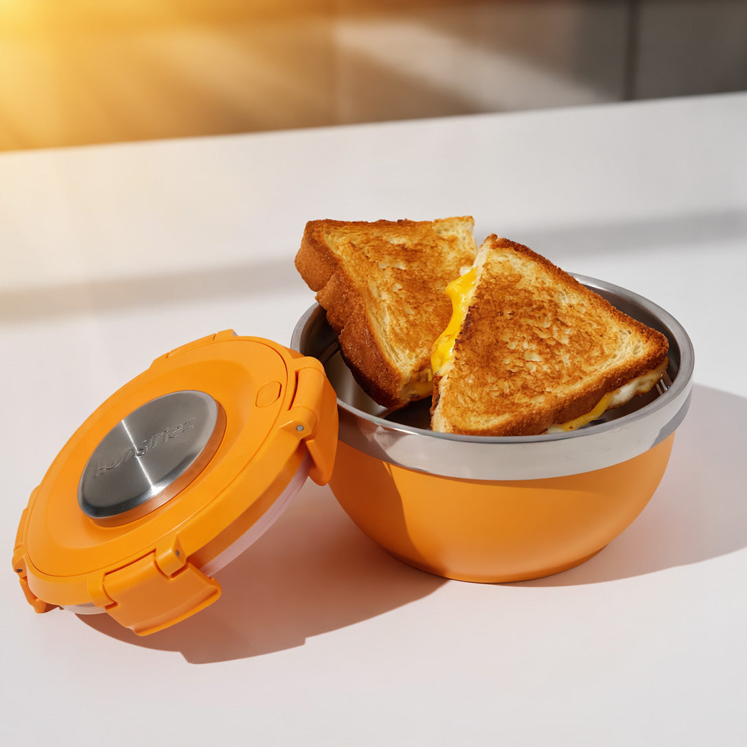 Orange lunch container with a grilled cheese sandwich on a white surface