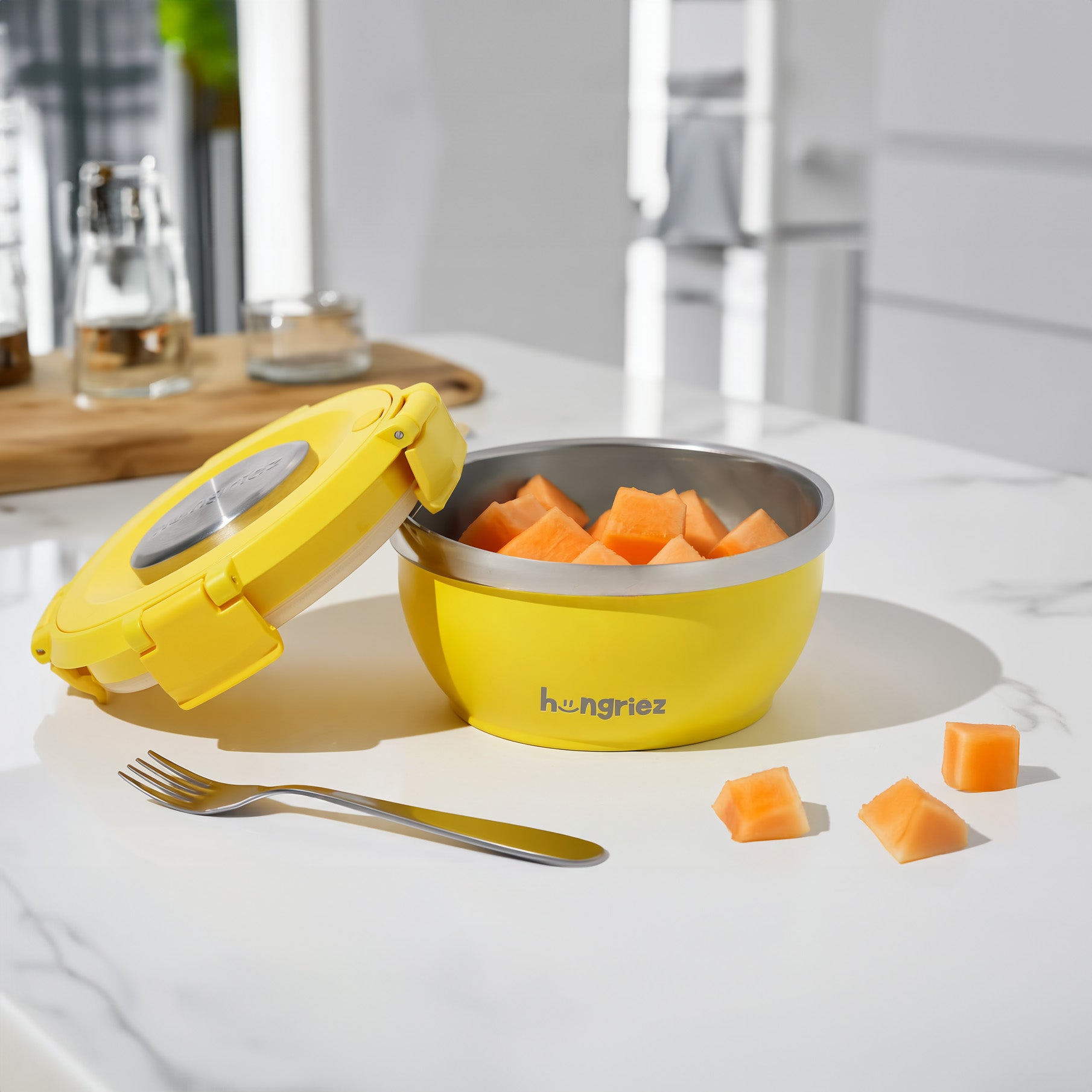 Yellow bowl like therosl with cantaloupe pieces on a kitchen counter.