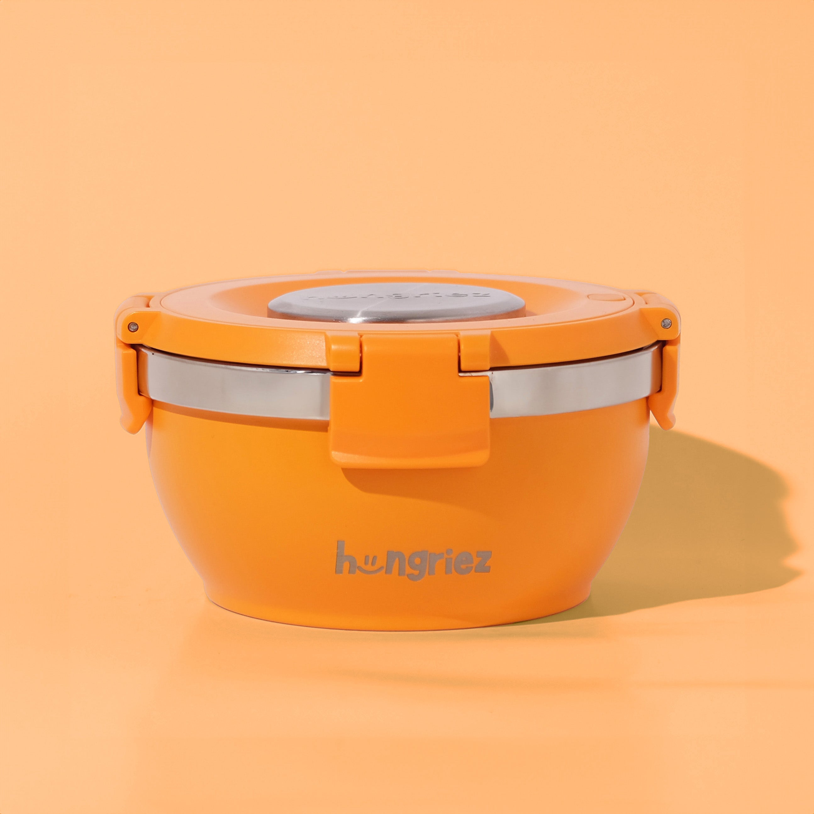 Orange lunch box with silver base on an orange background